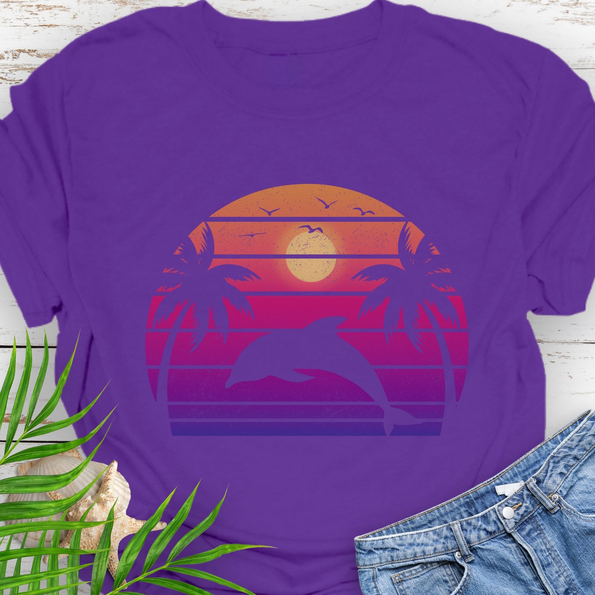 Purple T-shirt with a dolphin against a retro sunset and two palm trees.