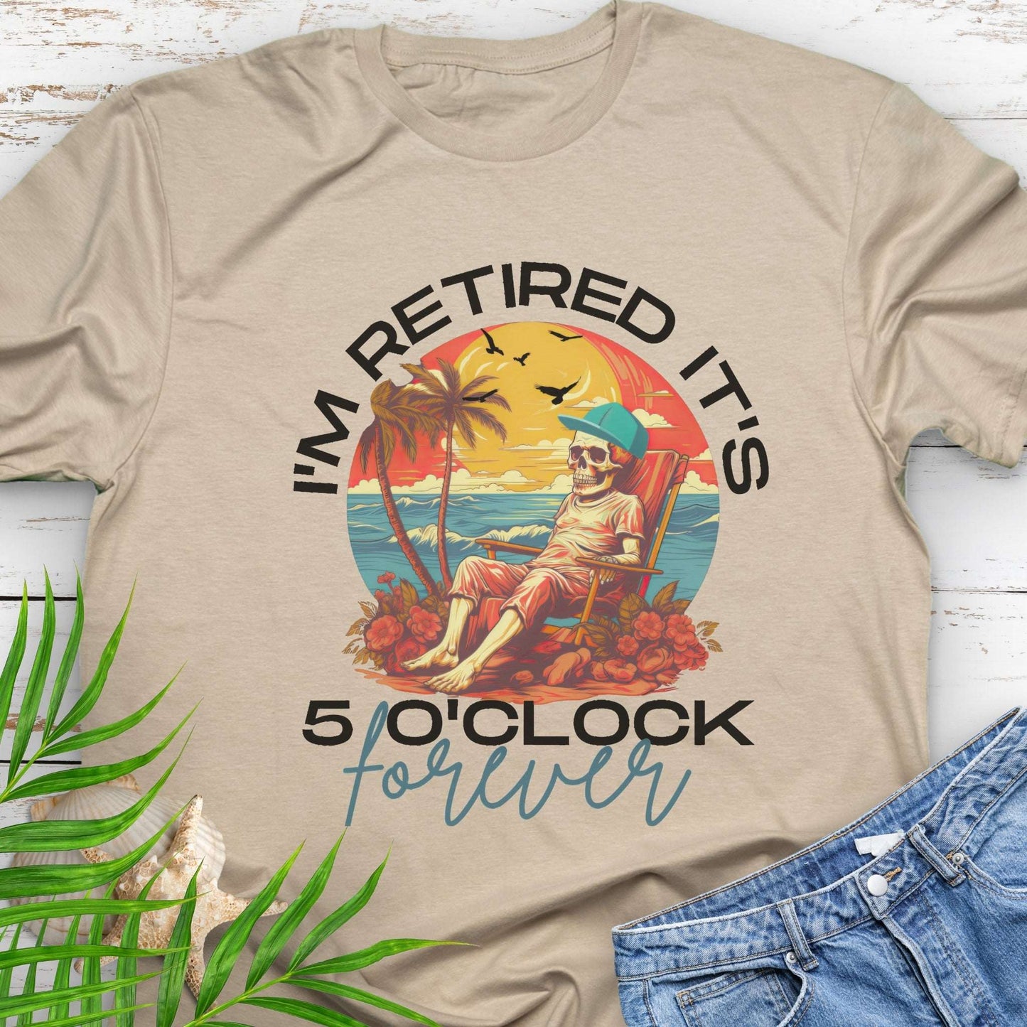 Beige t-shirt with a skeleton lounging on beach with text 'I'm Retired It's 5 0'Clock Forever.