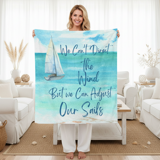 Woman holding a beach towel with a sailboat design and motivational quote in a living room.
