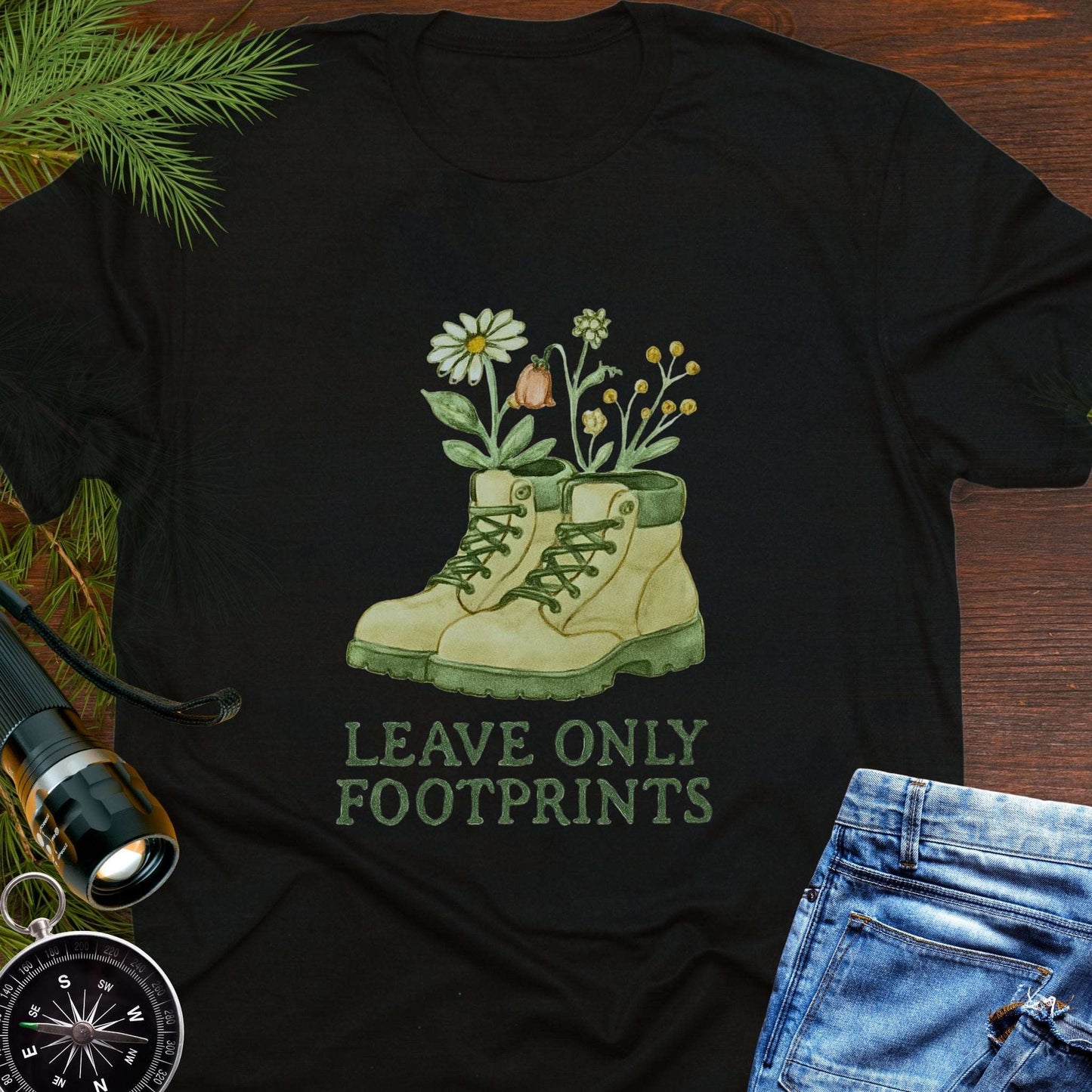 Black T-shirt with hiking boots and wildflowers that says "Leave Only Footprints."