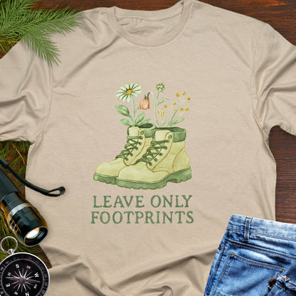 Beige T-shirt with hiking boots and wildflowers that says "Leave Only Footprints."