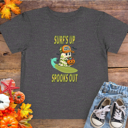 Gray toddler t-shirt with a cartoon ghost child on a surfboard, holding a pumpkin candy bucket, wearing an orange hat labeled “Candy Hunter,” with text that reads “Surf’s Up Spooks Out.”