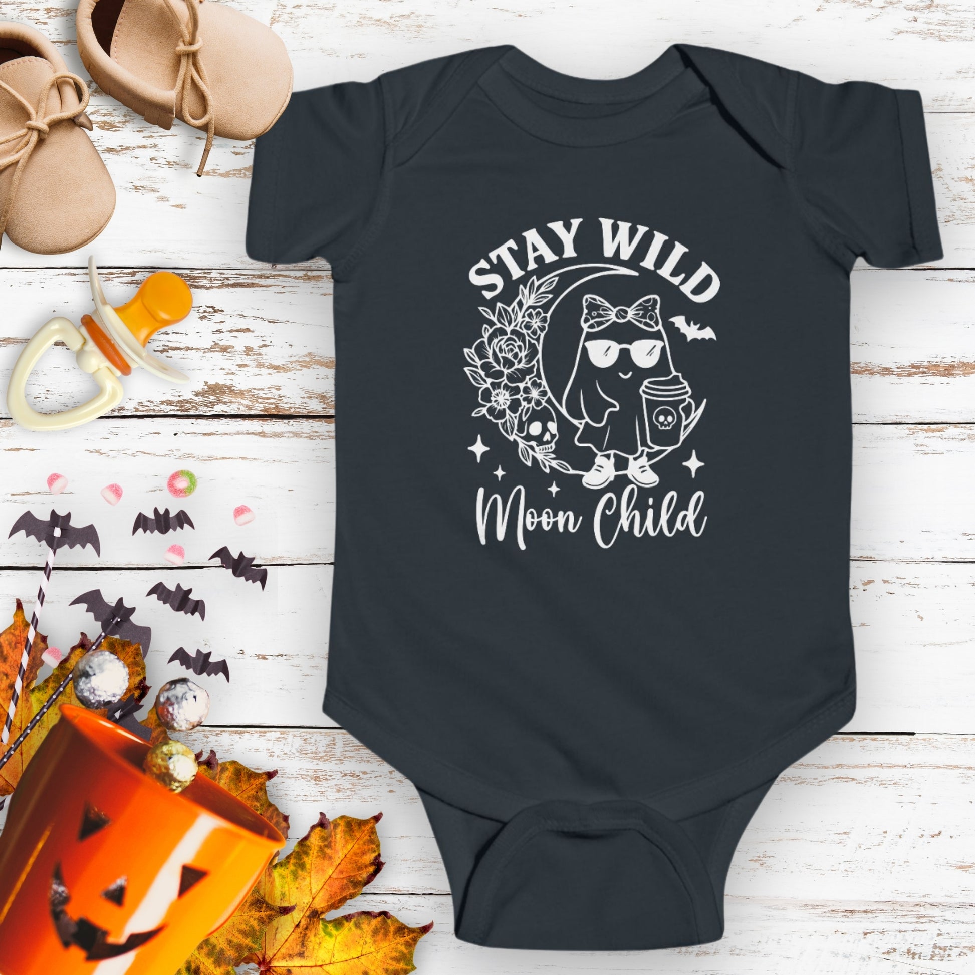 Black infant bodysuit featuring a girl ghost sitting on a crescent moon with floral accents and a skull design, with the text “Stay Wild Moon Child.”