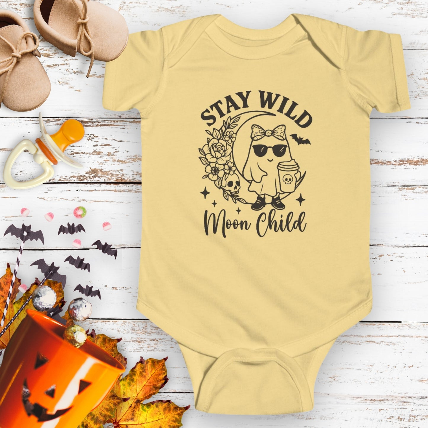 Yellow baby infant bodysuit featuring a girl ghost sitting on a crescent moon with floral accents and a skull design, with the text “Stay Wild Moon Child.”