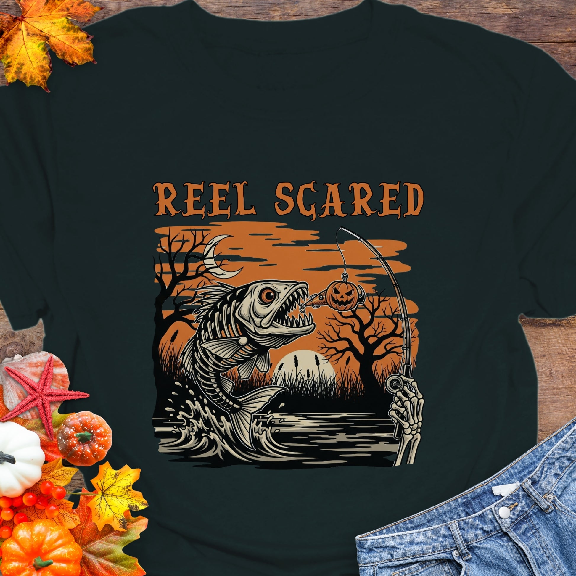 Black t-shirt with a skeleton fish going for a hook and the phrase “Reel Scared.