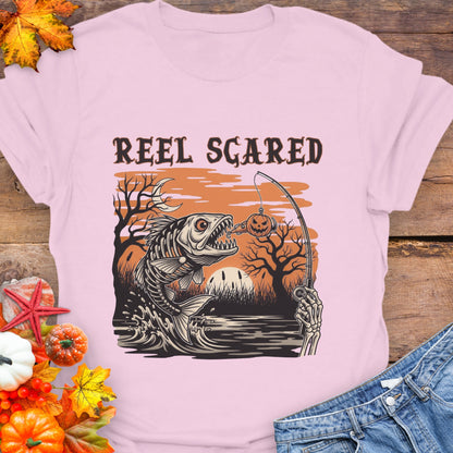 Pink t-shirt with a skeleton fish going for a hook and the phrase “Reel Scared.