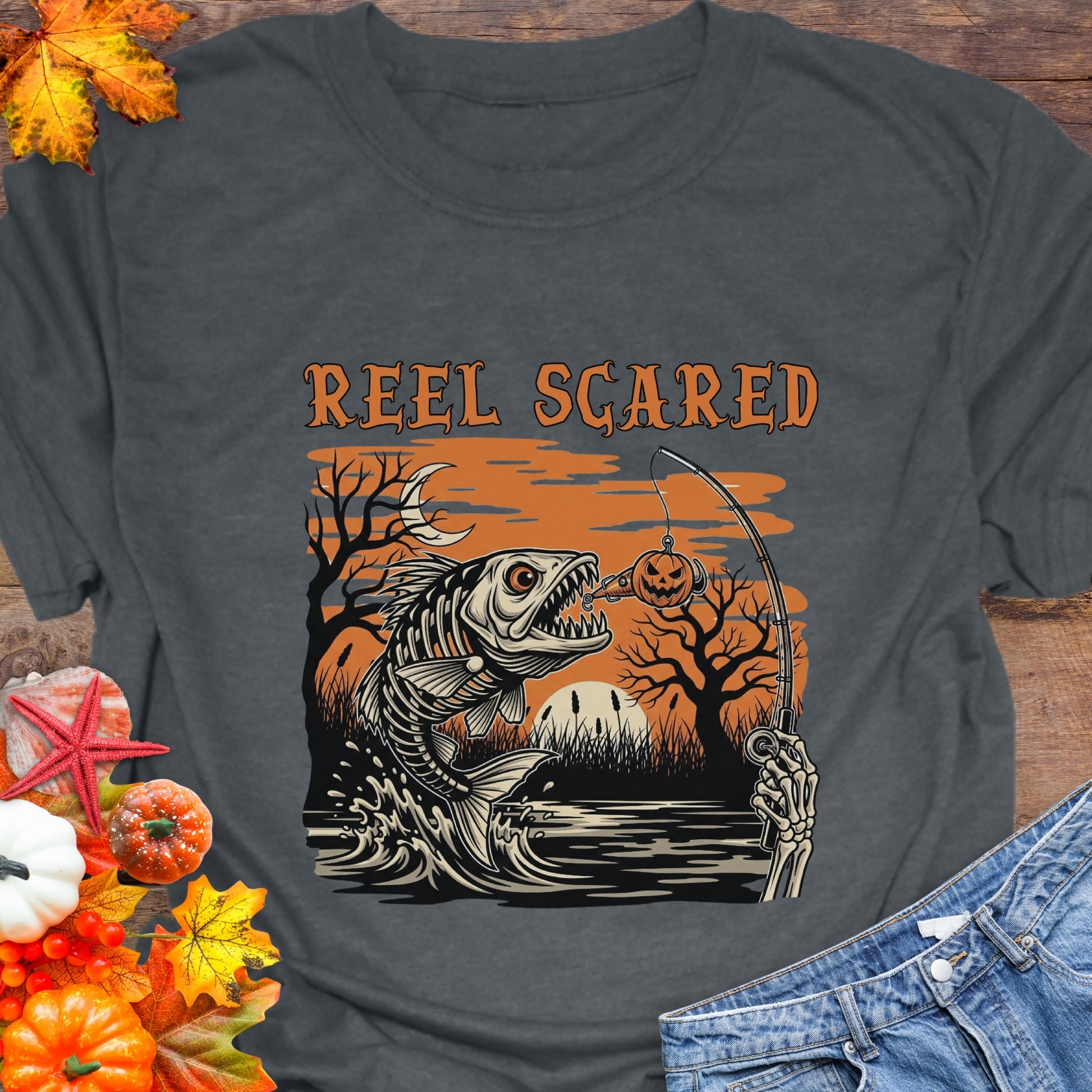 Gray t-shirt with a skeleton fish going for a hook and the phrase “Reel Scared.