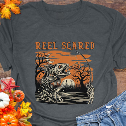 Gray t-shirt with a skeleton fish going for a hook and the phrase “Reel Scared.