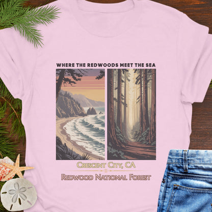 Pink t-shirt with nature-themed design featuring Redwood National Forest, displayed on a wooden surface with greenery and jeans.
