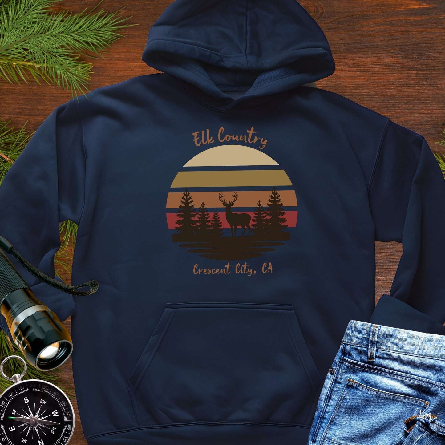 Navy blue hoodie with 'Elk Country' with retro sunset and silhouette of trees and elk design with Crescent City, CA underneath.