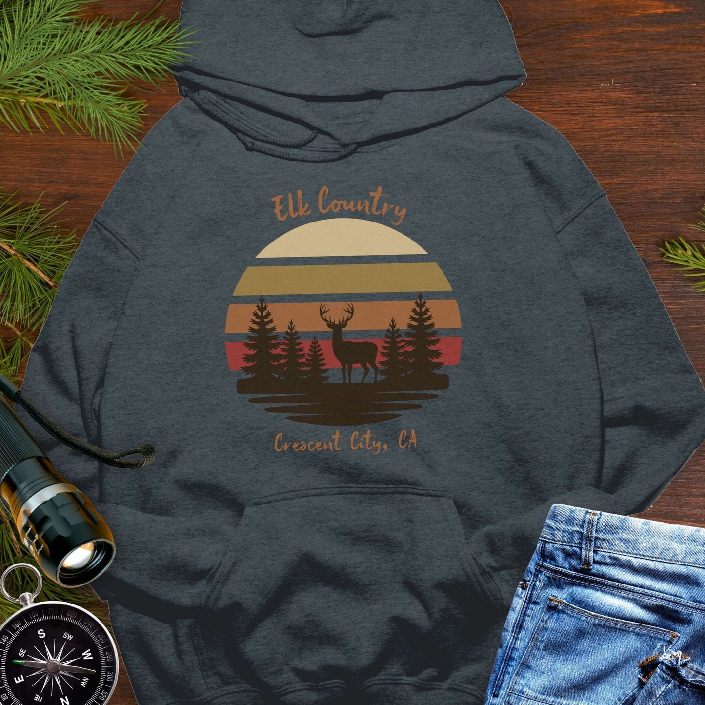 Dark heather gray hoodie with 'Elk Country' with retro sunset and silhouette of trees and elk design with Crescent City, CA underneath.