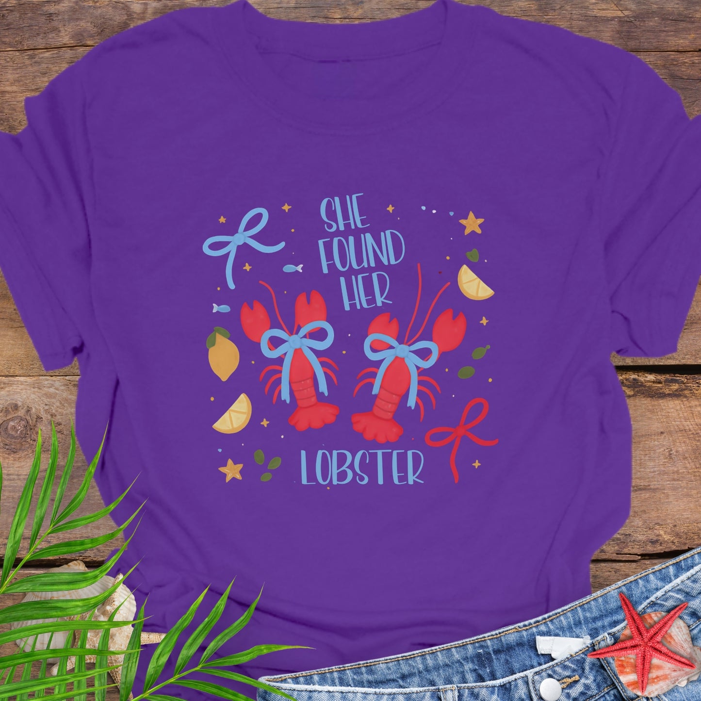 Purple T-shirt with two lobsters and blue bows that says She Found Her Lobster.