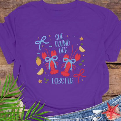 Purple T-shirt with two lobsters and blue bows that says She Found Her Lobster.