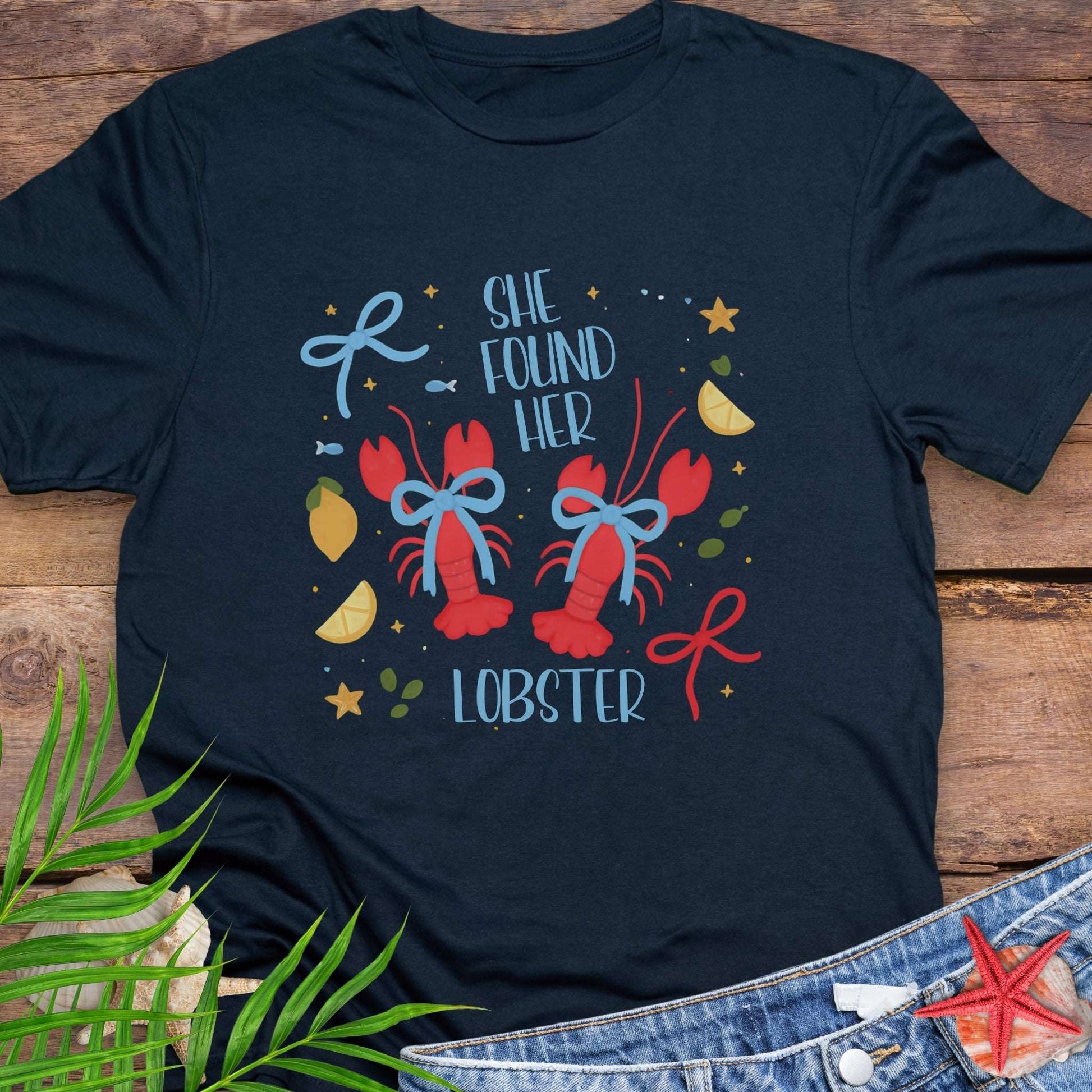 Navy Blue T-shirt with two lobsters and blue bows that says She Found Her Lobster.