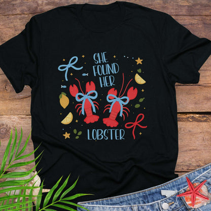 Black T-shirt with two lobsters and blue bows that says She Found Her Lobster.