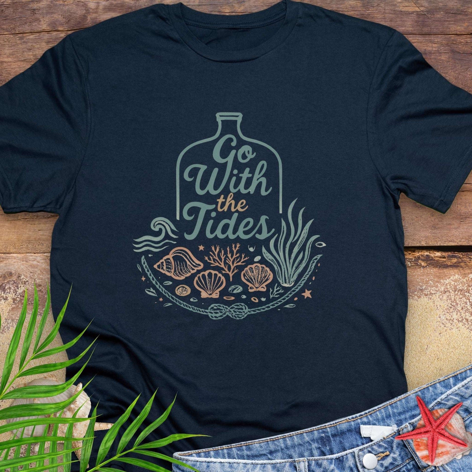 Navy blue Go With the Tides t-shirt with ocean bottle design, seashells, and coral artwork.