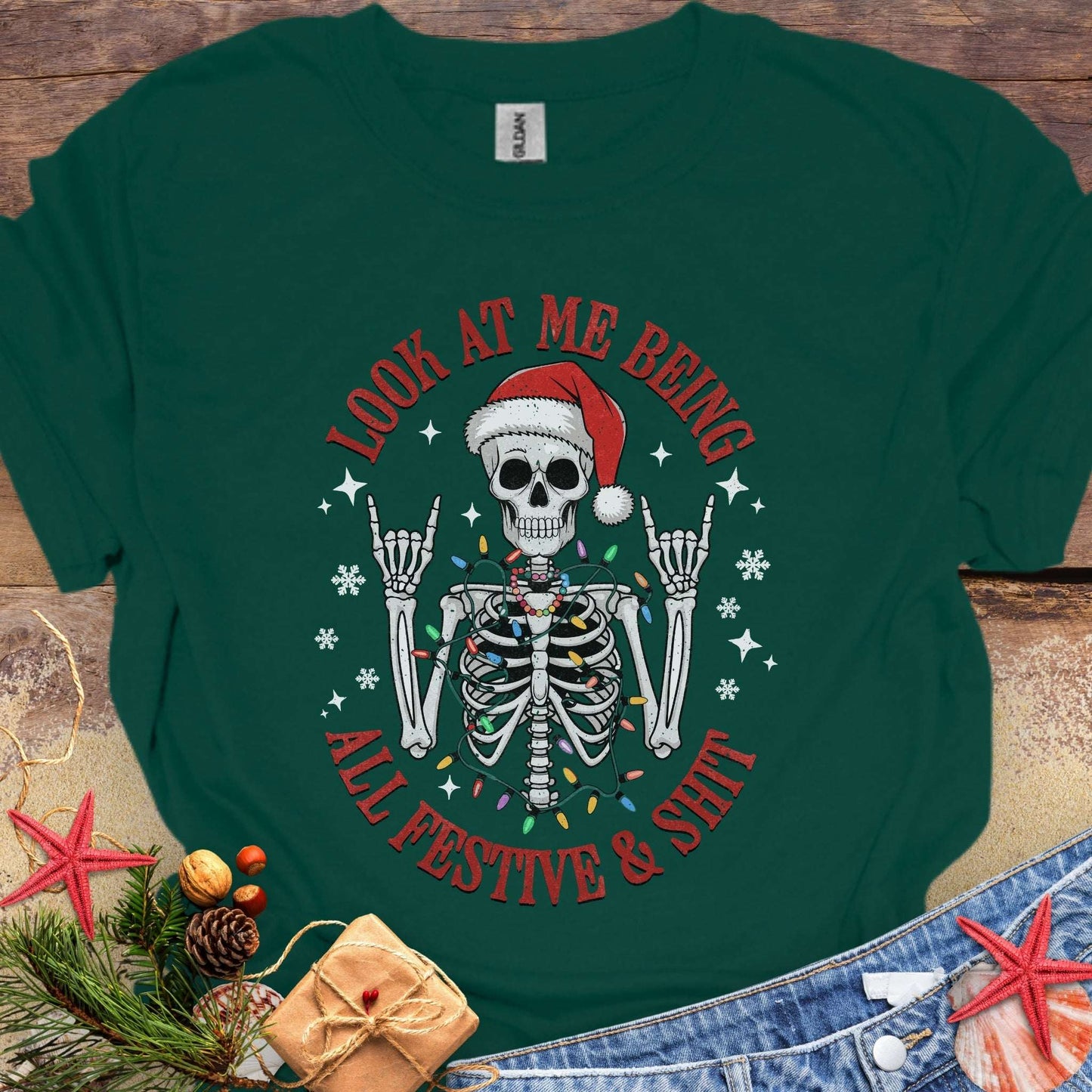 Green t-shirt with skeleton wearing a Santa hat and lights wrapped around body design and text 'Look at me being all festive and shit.