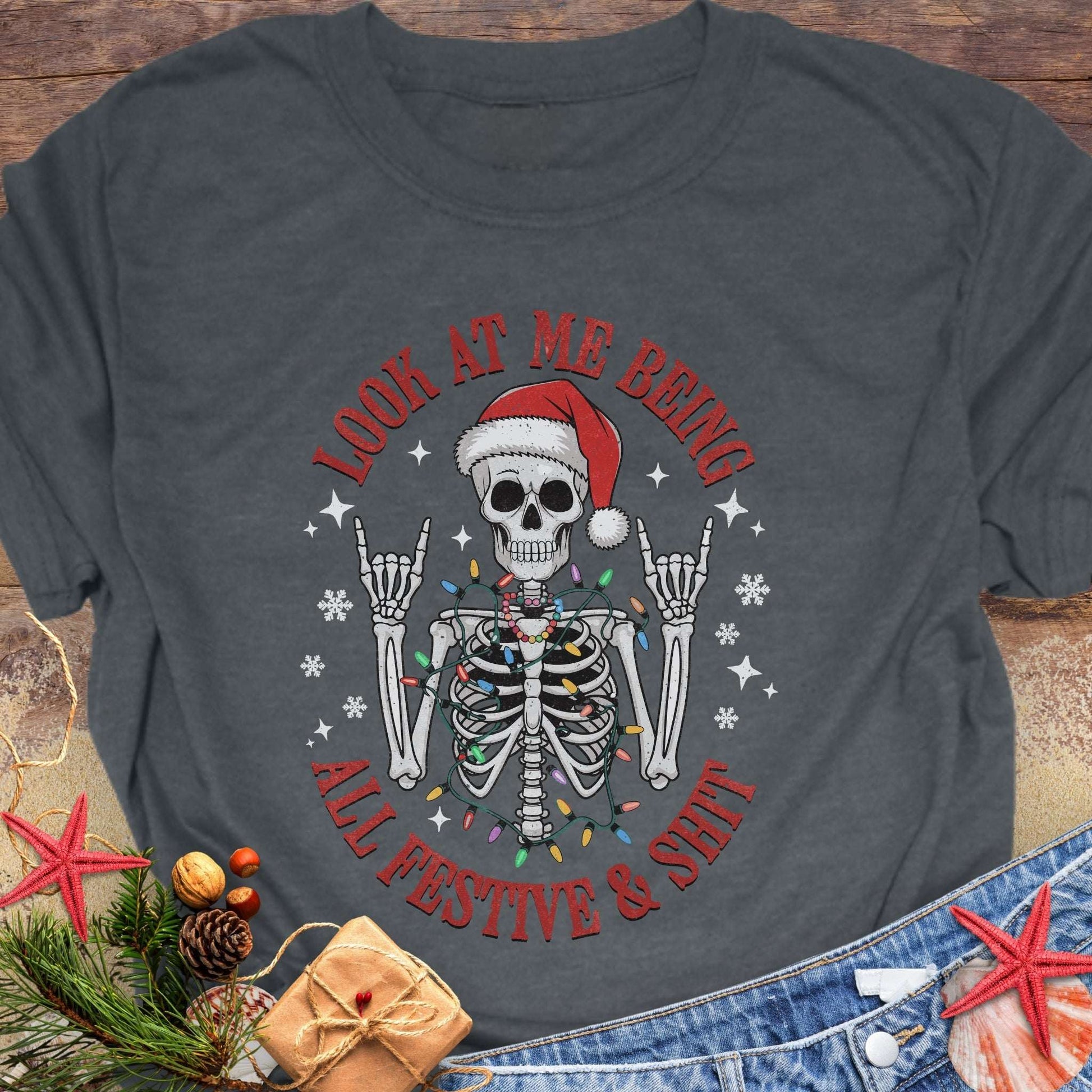 Gray t-shirt with skeleton wearing a Santa hat and lights wrapped around body design and text 'Look at me being all festive and shit.