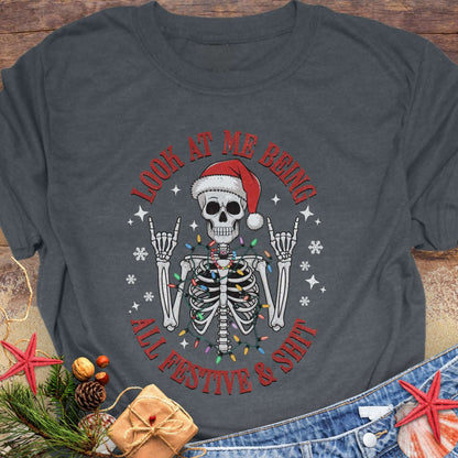 Gray t-shirt with skeleton wearing a Santa hat and lights wrapped around body design and text 'Look at me being all festive and shit.