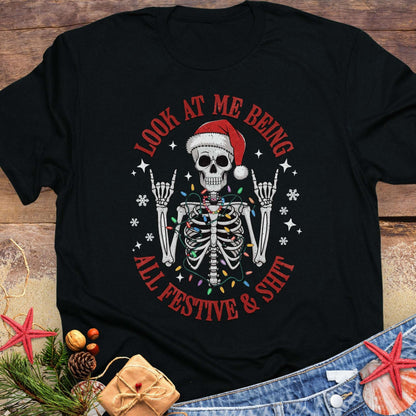 Black t-shirt with skeleton wearing a Santa hat and lights wrapped around body design and text 'Look at me being all festive and shit.