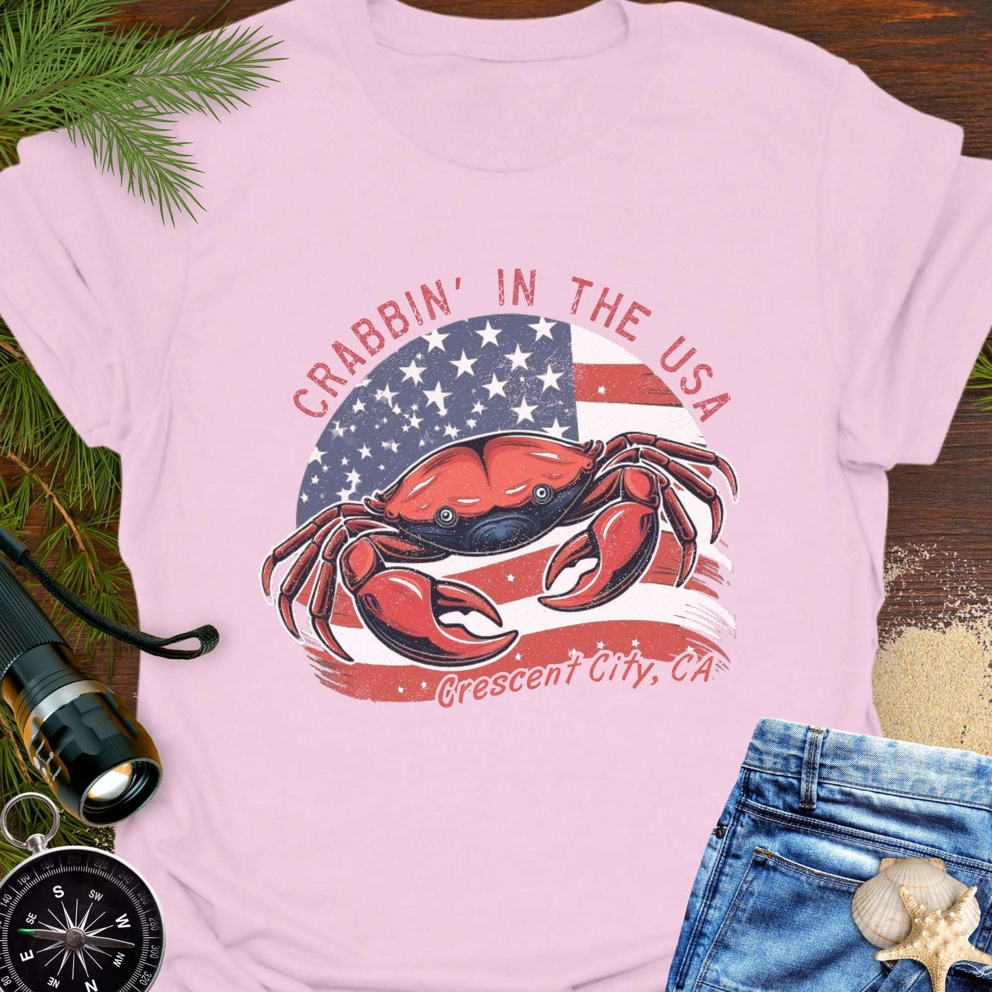 Pink t-shirt with a crab and American flag design and text 'Crabbin' in the USA – Crescent City, CA'. 