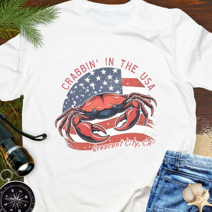 White t-shirt with a crab and American flag design and text 'Crabbin' in the USA – Crescent City, CA'. 