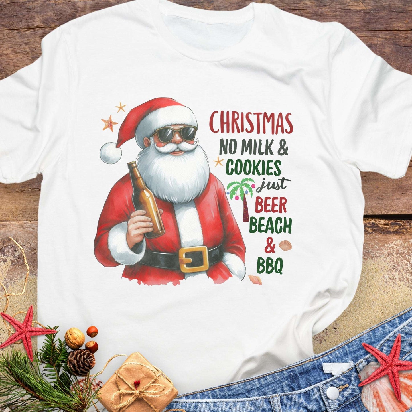 White t-shirt with a graphic of Santa Claus holding a beer, text 'Christmas No Milk & Cookies Just Beer Beach & BBQ'.