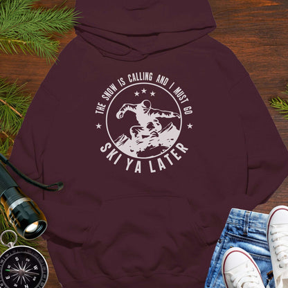 Maroon hoodie with skiing graphic and text 'The snow is calling and I must go Ski Ya Later'.