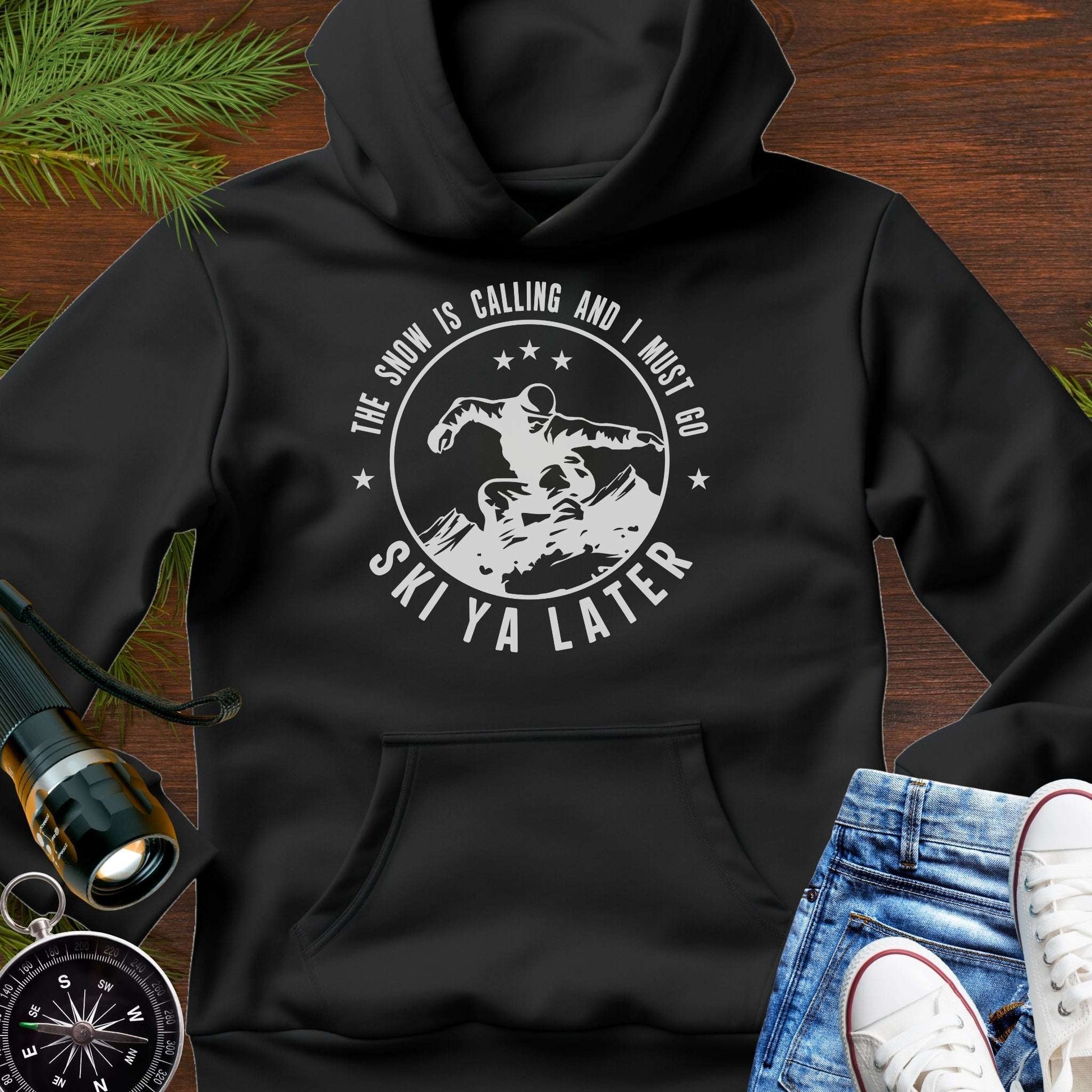 Black hoodie with skiing graphic and text Snow Is Calling – Ski Ya Later.