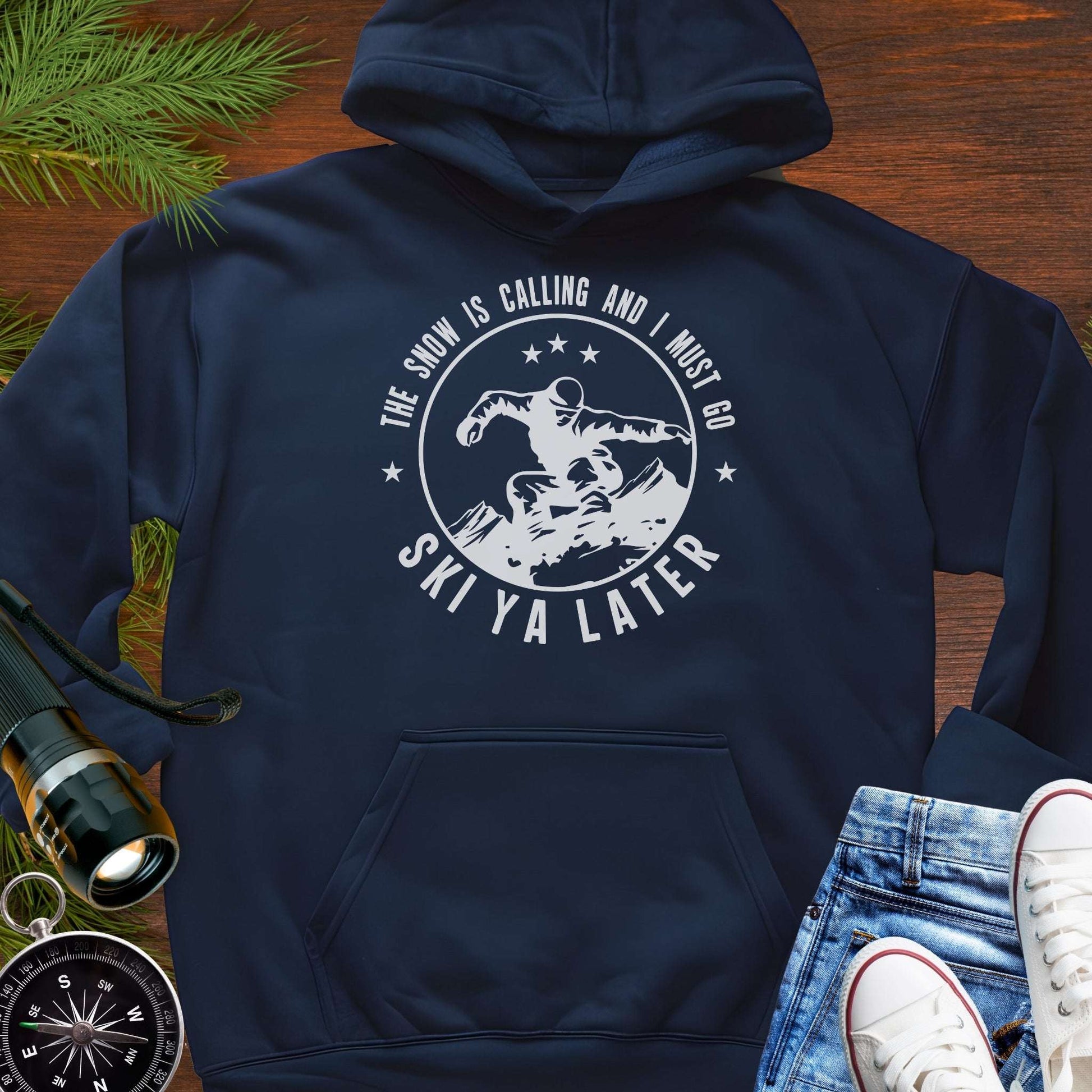 Navy blue hoodie with skiing graphic and text 'The snow is calling and I must go Ski Ya Later'.