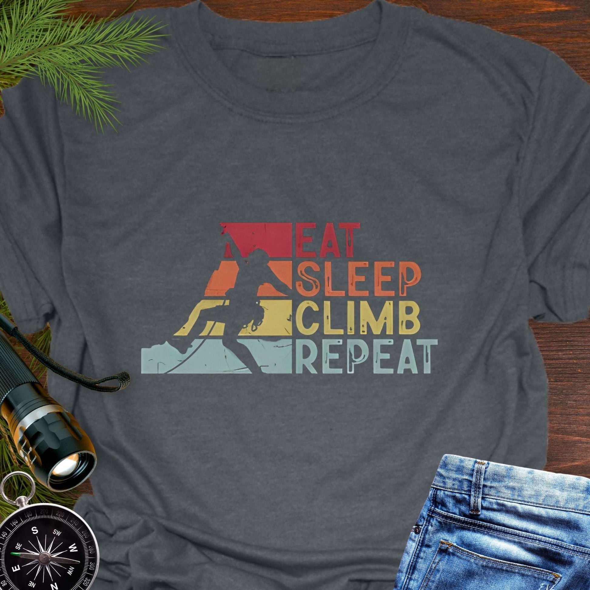 Gray t-shirt with 'Eat Sleep Climb Repeat' graphic on a wooden surface with climbing accessories.