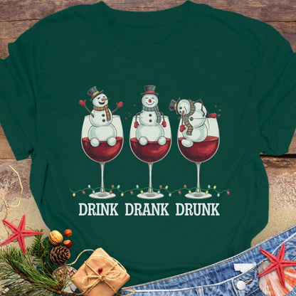 Green T-shirt with three snowmen sitting inside large wine glasses, raising smaller glasses above the text “DRINK DRANK DRUNK.