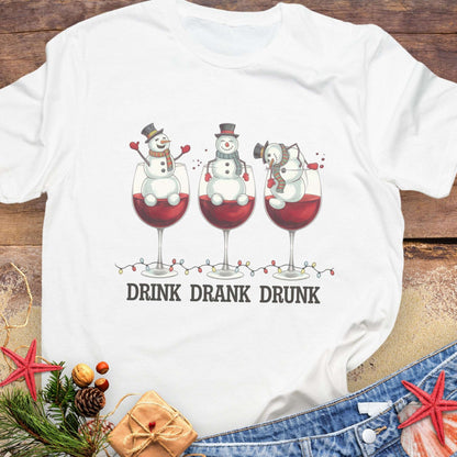 White T-shirt with three snowmen sitting inside large wine glasses, raising smaller glasses above the text “DRINK DRANK DRUNK.