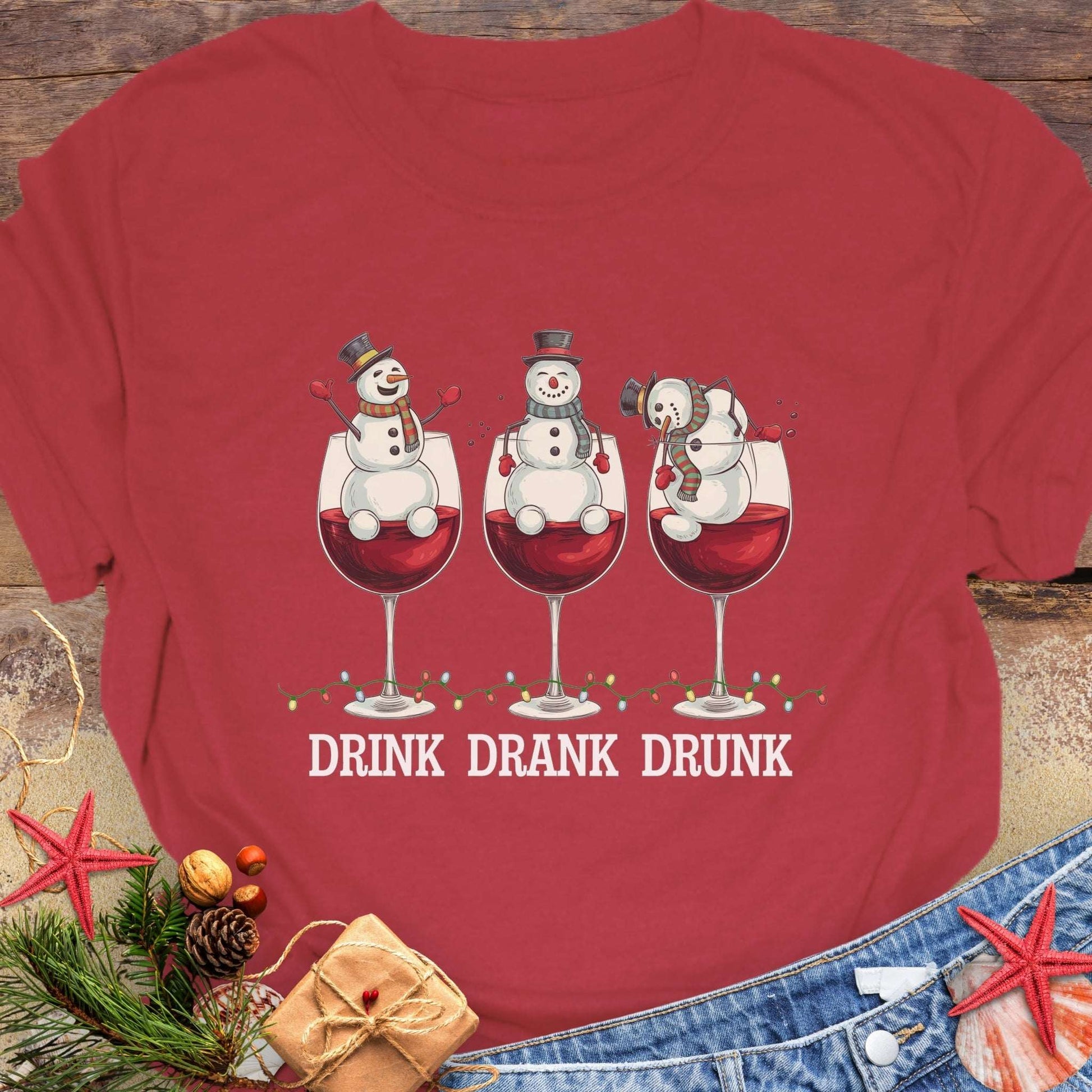 Red T-shirt with three snowmen sitting inside large wine glasses, raising smaller glasses above the text “DRINK DRANK DRUNK.