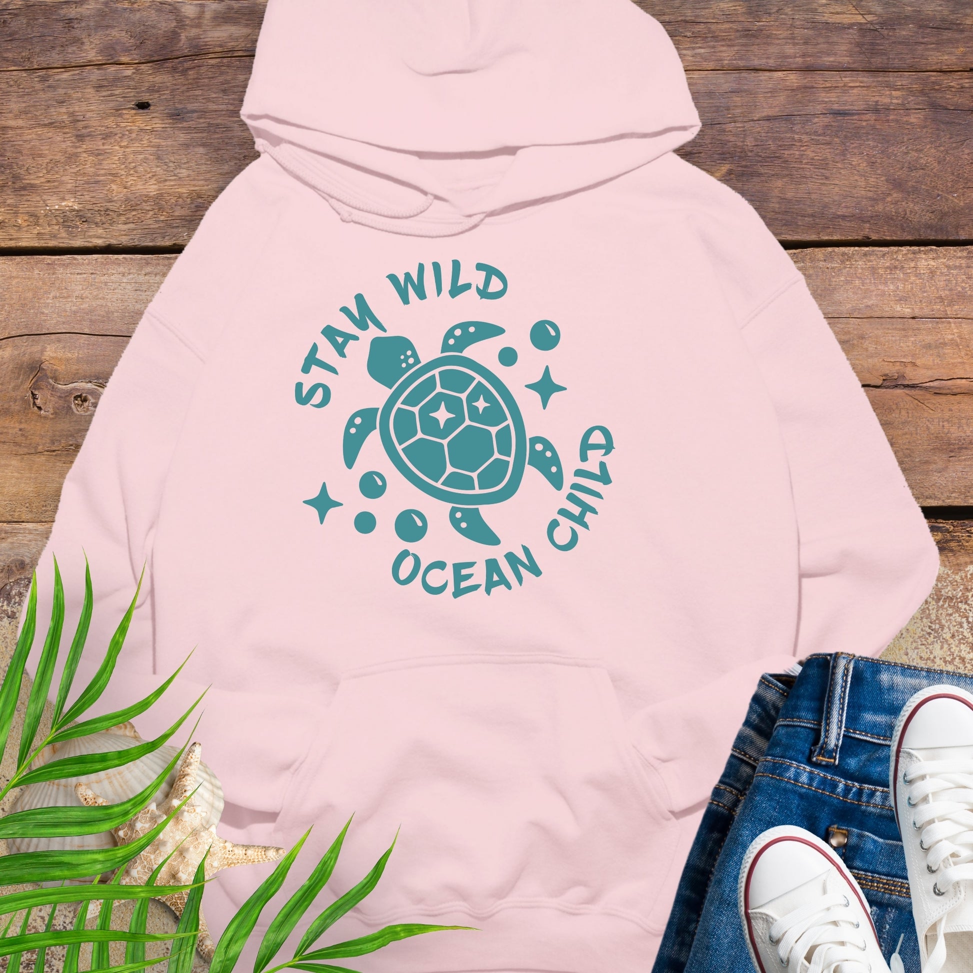 Pink hoodie with a sea turtle design and text Stay Wild Ocean Child.