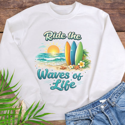 White crewneck sweatshirt with inspirational Ride the Waves of Life beach design, showing surfboards, ocean sunset, palm leaves, and sand.