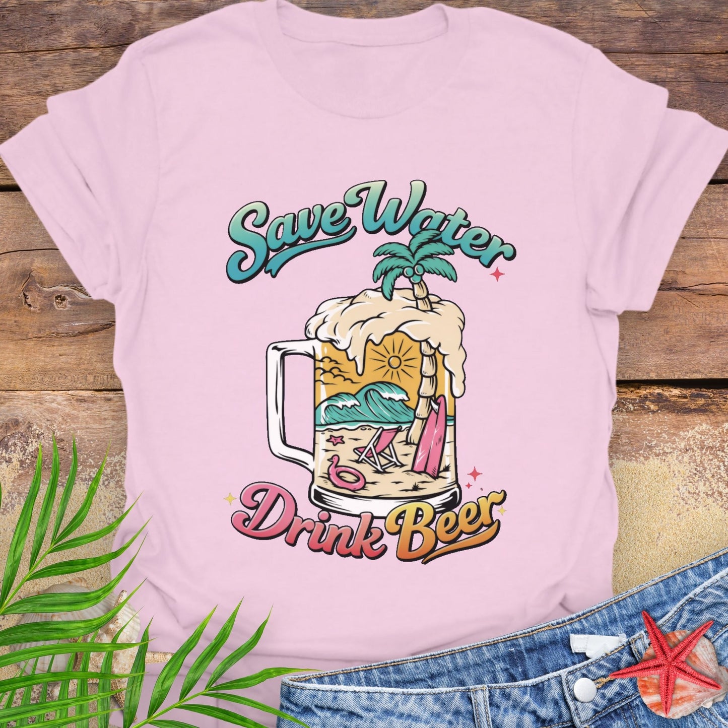 Pink unisex t-shirt with “Save Water Drink Beer” in colorful retro text and a beach scene inside a beer mug.