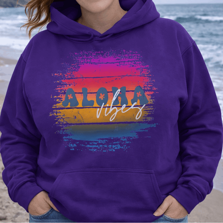 Woman wearing a purple hoodie with 'Aloha Vibes' design on a beach