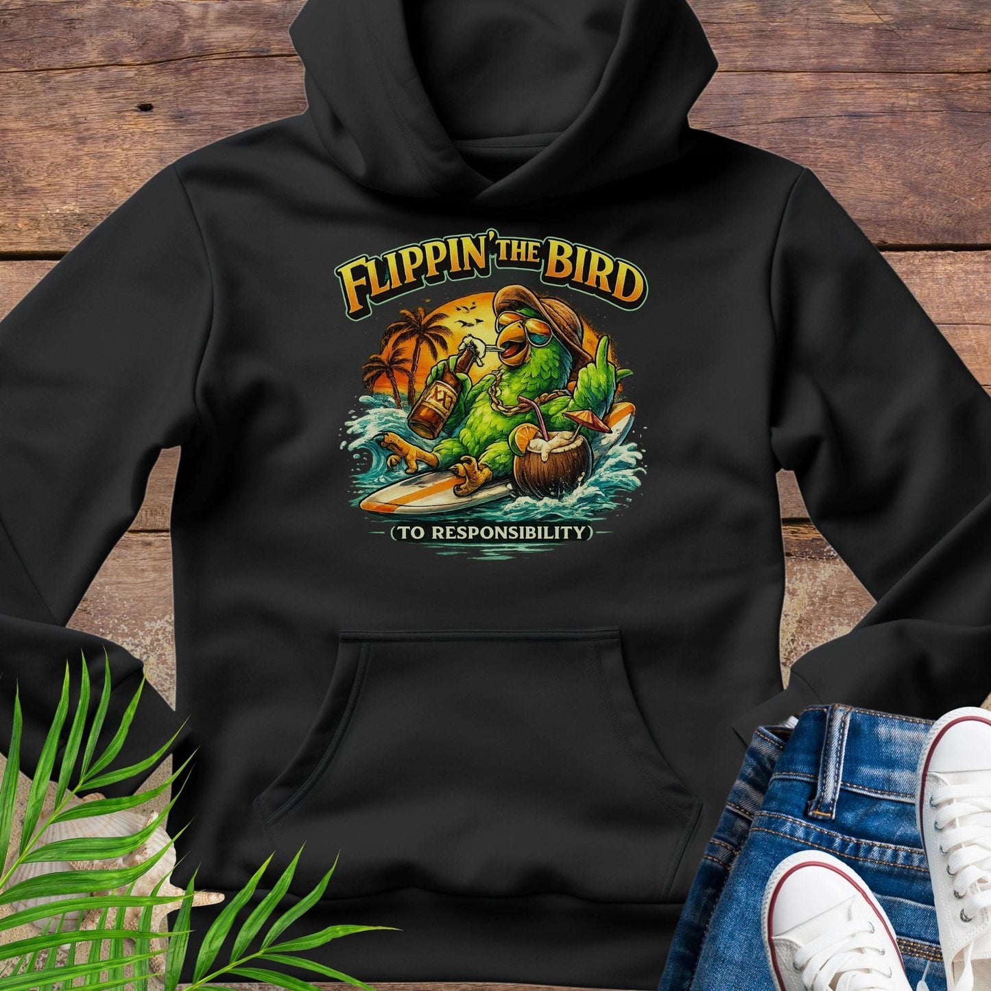 Black tropical graphic hoodie featuring a green parrot surfing with sunglasses, holding a beer, with coconut drink and sunset palms; text reads “Flippin’ the Bird (to responsibility)”.