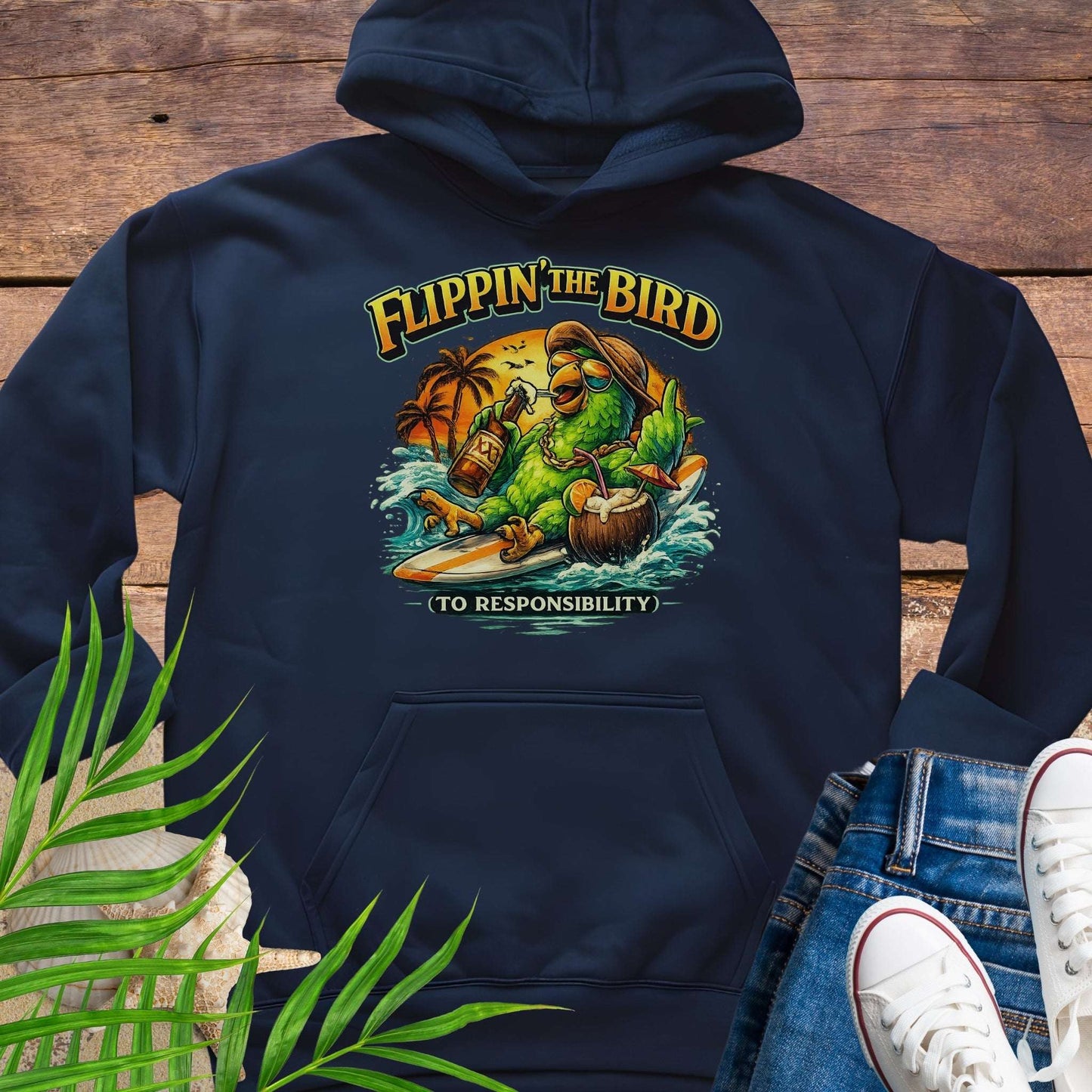 Navy blue tropical graphic hoodie featuring a green parrot surfing with sunglasses, holding a beer, with coconut drink and sunset palms; text reads “Flippin’ the Bird (to responsibility)”.