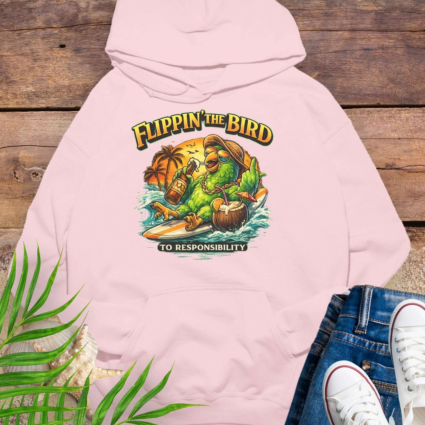 Light Pink tropical graphic hoodie featuring a green parrot surfing with sunglasses, holding a beer, with coconut drink and sunset palms; text reads “Flippin’ the Bird (to responsibility)”.