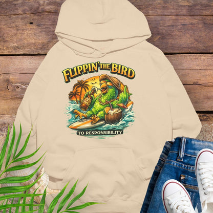 Beige tropical graphic hoodie featuring a green parrot surfing with sunglasses, holding a beer, with coconut drink and sunset palms; text reads “Flippin’ the Bird (to responsibility)”.