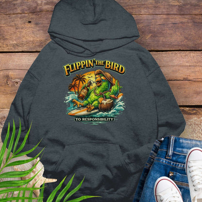 Dark Heather Gray tropical graphic hoodie featuring a green parrot surfing with sunglasses, holding a beer, with coconut drink and sunset palms; text reads “Flippin’ the Bird (to responsibility)”.