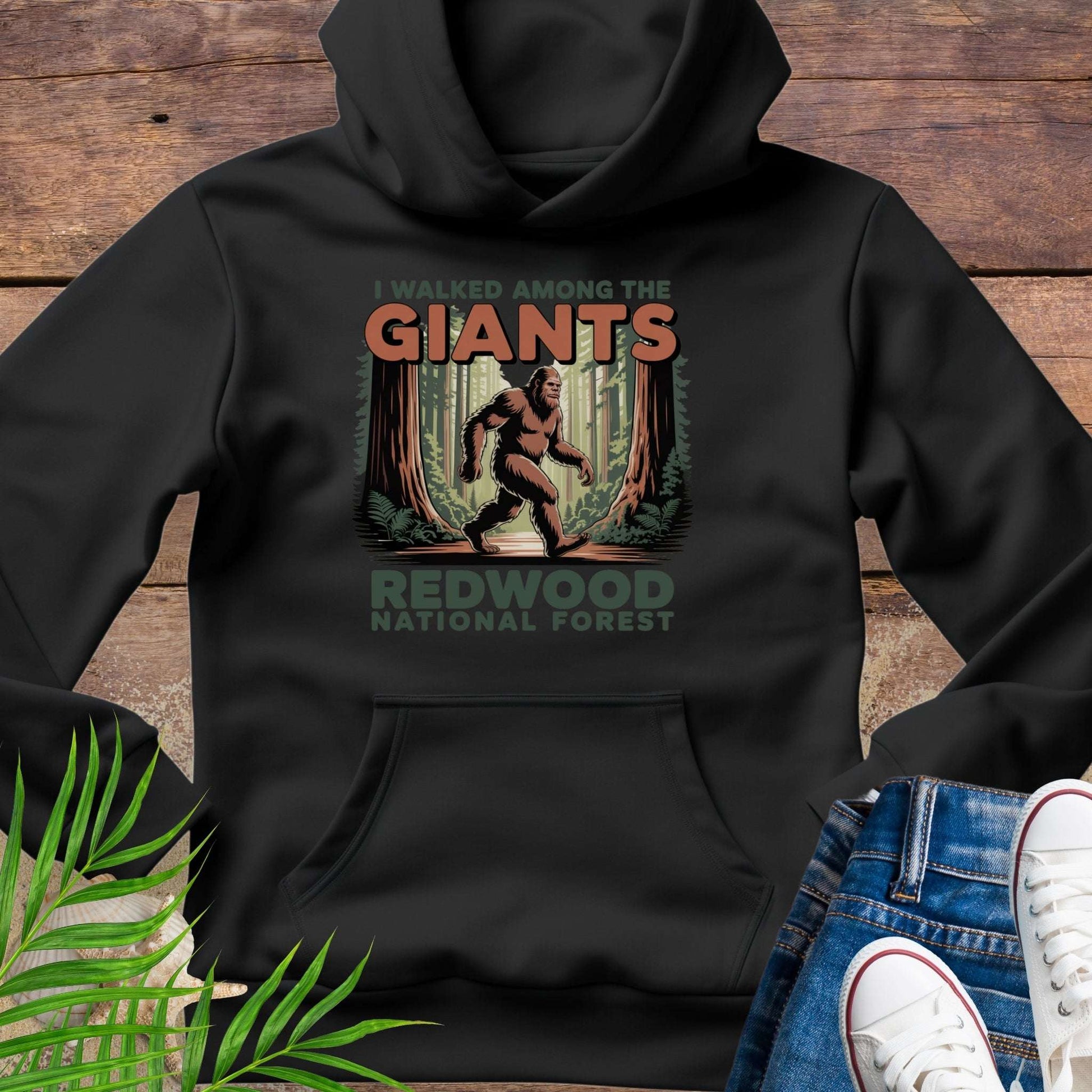 Black hoodie with 'I Walked Among the Giants' Redwood National Forest design on a wooden surface.