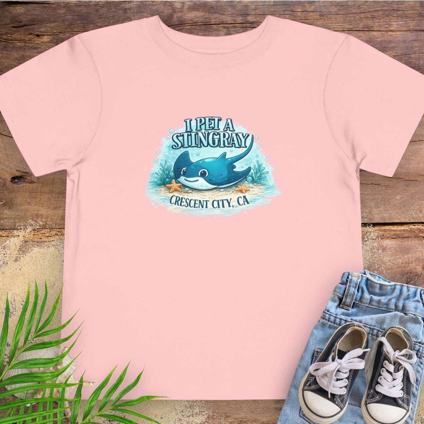 Pink t-shirt with a stingray graphic and text 'I Pet a Stingray Crescent City, CA'.