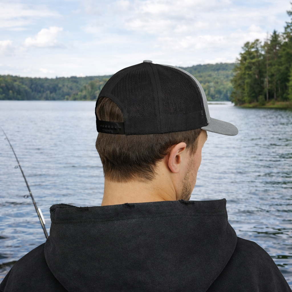 Person wearing a black mesh with gray front trucker hat.