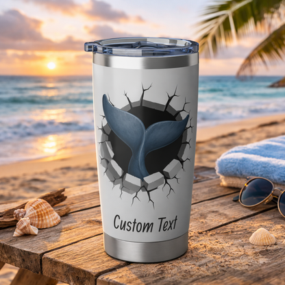 Silver tumbler with a shark design on a beach at sunset