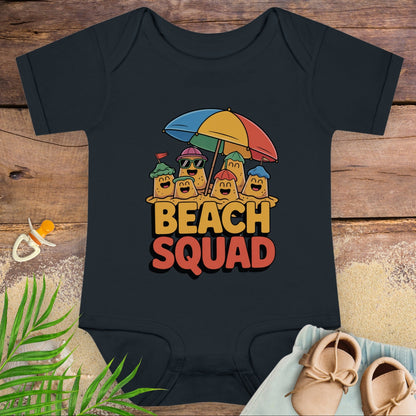 Black baby onesie with 'Beach Squad' design on a wooden surface with a pacifier and shoes.