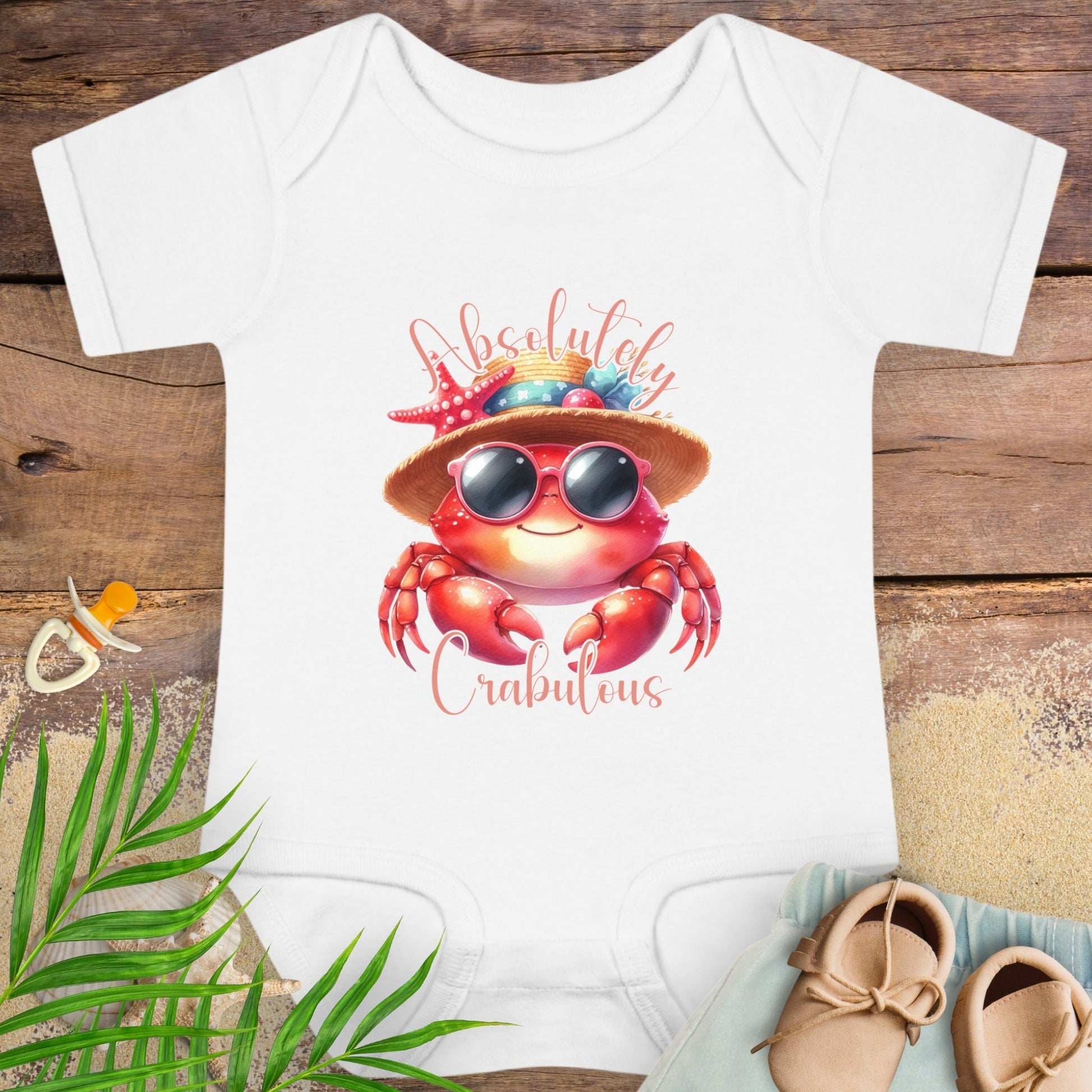 White baby onesie with a red crab design wearing sunglasses and a hat with text Absolutely Crabulous.