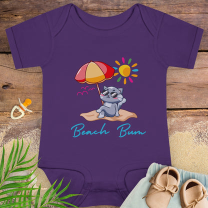 Purple baby onesie with a beach-themed design with a cat lounging on a sandy beach.